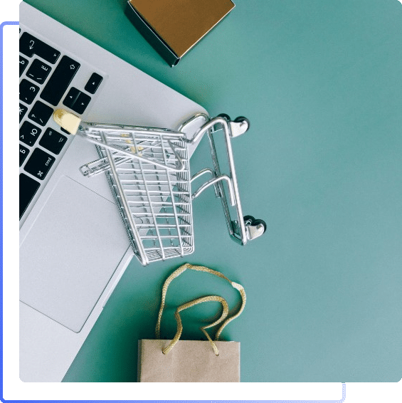 Shopping cart and shopping bags next to laptop keyboard
